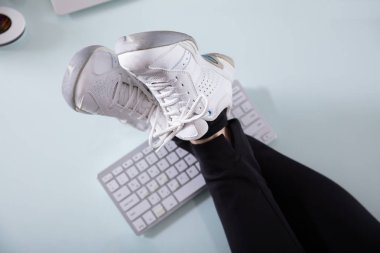 Bilgisayar klavye üzerinde ayakkabı ile bir iş kadını'nın çapraz bacak yüksek açılı görünüş