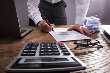 İşadamı'nın el ahşap masa hesap makinesiyle Bill hesaplama