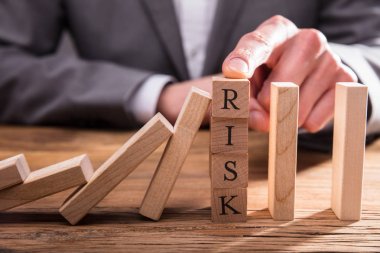 İşadamı'nın parmak üzerinde Risk ahşap bloklar masanın üstüne düşmesini Dominos durdurma