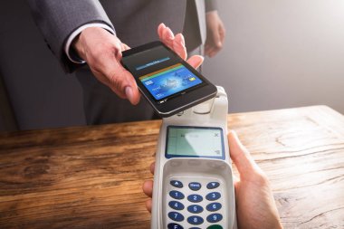 Bir işadamının'ın el ile Smartphone üzerinde ahşap Resepsiyon Nfc teknolojisini kullanarak ödeme Close-Up