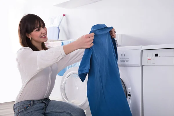 Sonriente Joven Mujer Mirando Limpio Azul Camiseta Lavadero — Foto de Stock