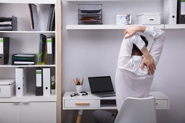 オフィスの彼の腕を伸ばして実業家の背面図 — ストック写真