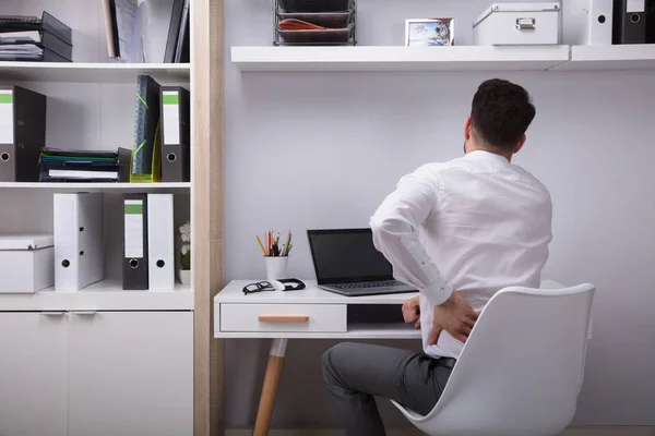 職場で背中の痛みに苦しむビジネスマンの背面図 — ストック写真
