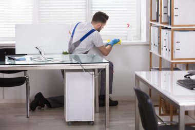 Genç erkek hademe pencere pervazına sünger Office ile Temizleme