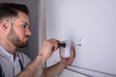 Genç bir erkek elektrikçi güvenlik sistemi kapı sensör duvara yükleme yakın çekim