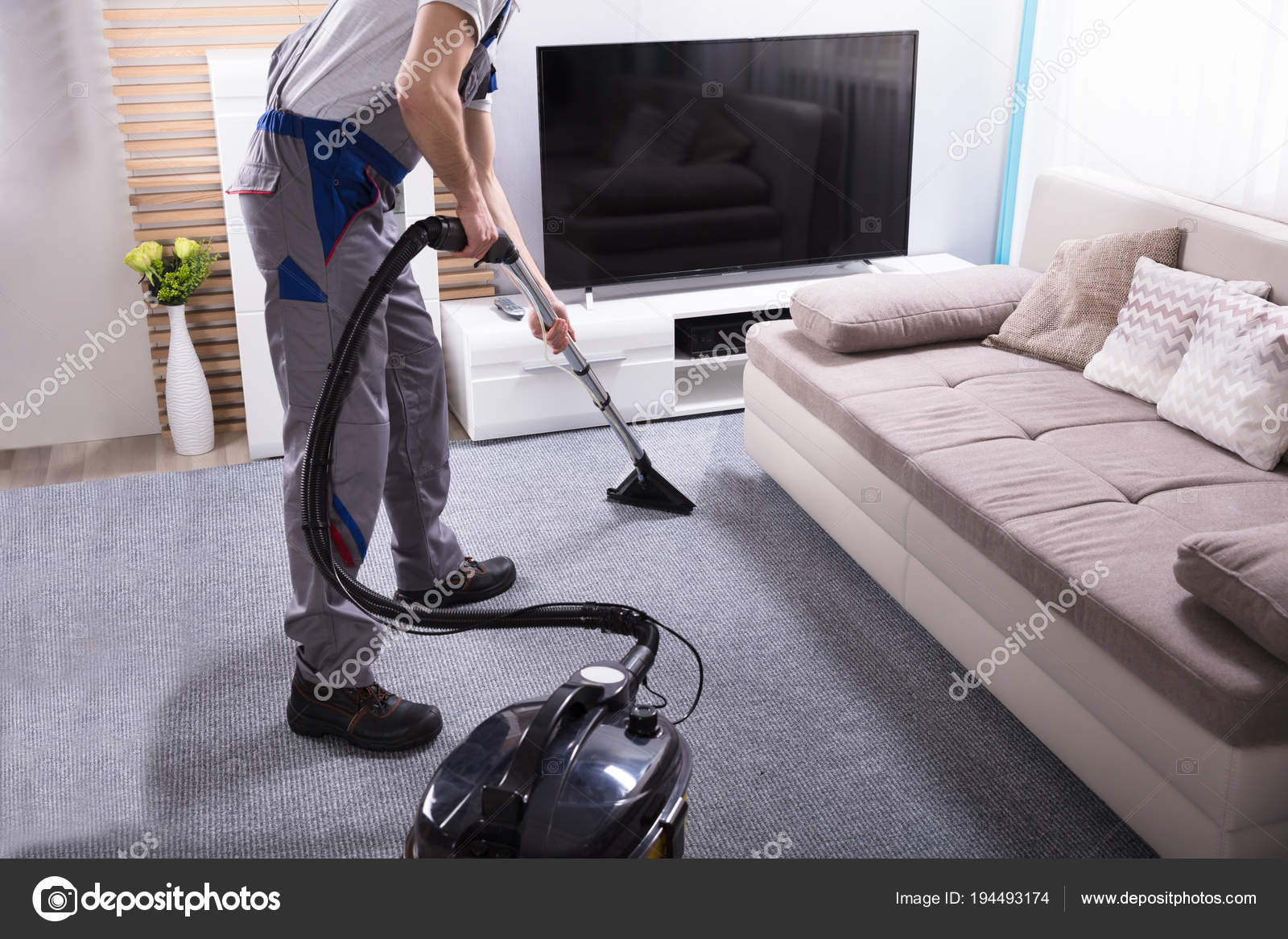 Close Male Janitor Using Vacuum Cleaner Cleaning Carpet Living Room