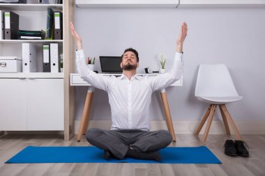 Meditasyon yaparken kollarını yükselterek genç işadamı