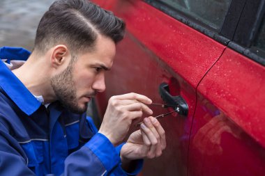 Young Man Opening Red Car Door With Lockpicker clipart