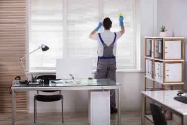 Bir erkek işçinin pencere Panjur sünger Office ile temizlik arkadan görünüş
