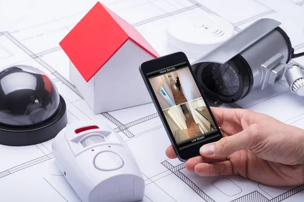 Architect Using Home Security System On Mobile Phone Near Security Equipments And House Model