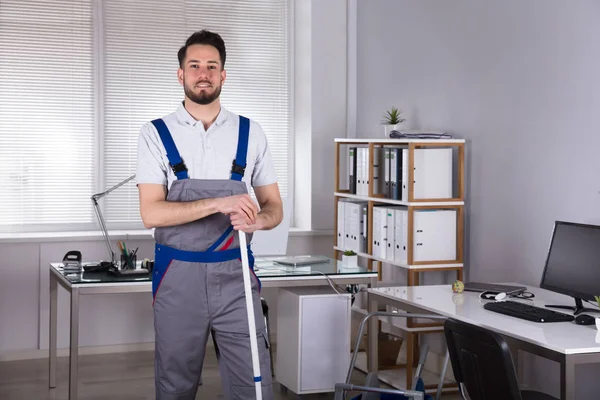 Portrait Smiling Young Male Janitor Standing Broom Office — Stock Photo, Image