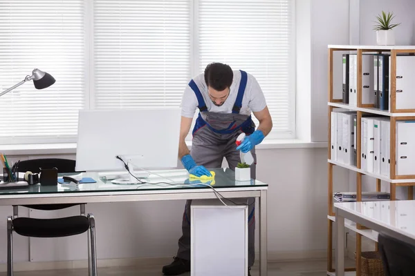 Young Male Worker Using Spray Cleaning Office Desk — Stock Photo, Image