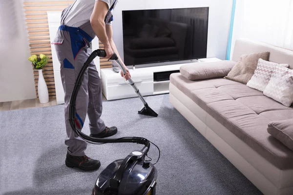 リビングでカーペットをきれいにするために掃除機を使用して男性清掃員のクローズアップ — ストック写真