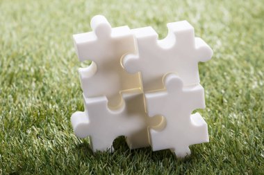 Dört beyaz Jigsaw Puzzle yükseltilmiş görünümünü yeşil çimenlerin üzerinde