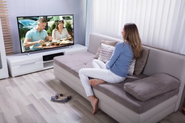 Evde televizyon izlerken koltukta oturan kadın olgun