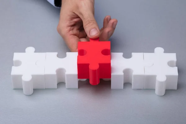 Person Hand Placing Red Piece White Jigsaw Puzzle — стоковое фото