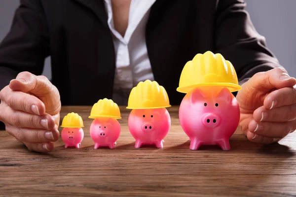 Ondernemer Hand Bescherming Stijgende Roze Piggybanks Met Gele Veiligheidshelm — Stockfoto