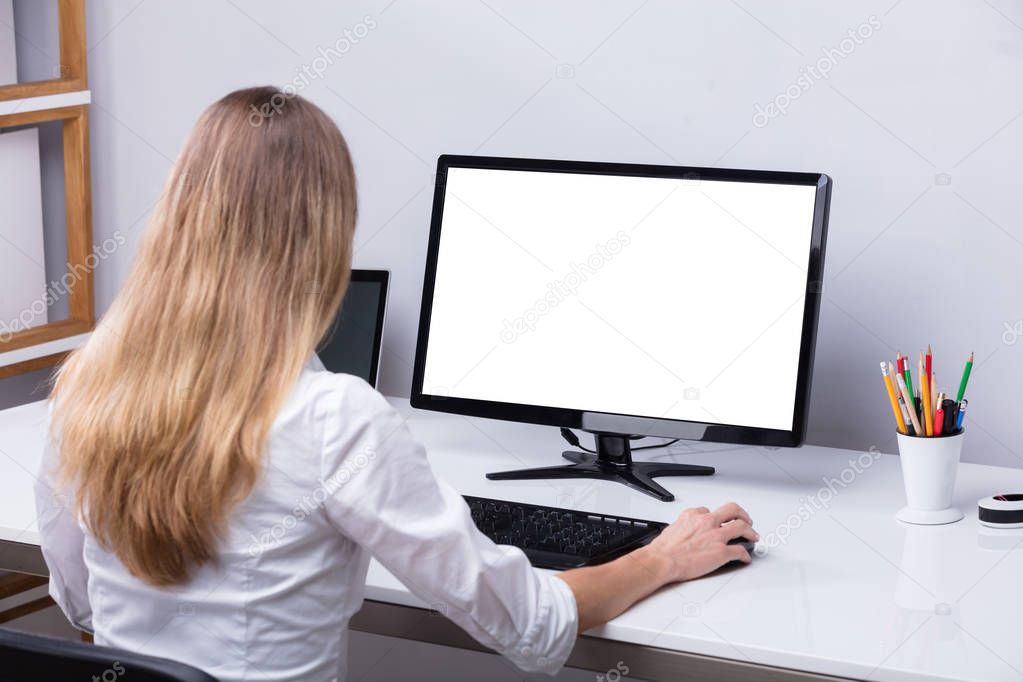 Businesswoman Using Computer With Blank White Screen At Workplace