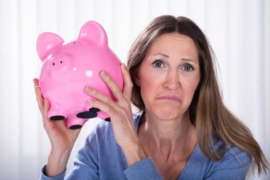 Piggybank güneşlikler karşı tutan mutsuz kadın Close-Up
