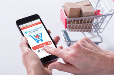 Uygulama Online alışveriş sepeti ile cep telefonu kullanan bir kişi yakın çekim