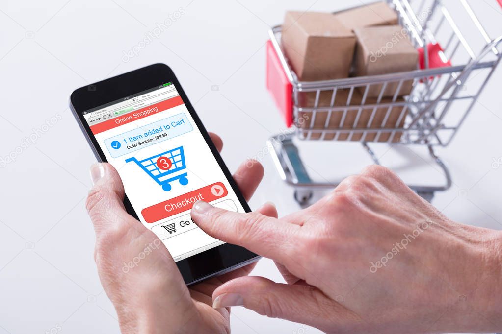 Close-up Of A Person Using Online Shopping Application On Mobile Phone With Cart