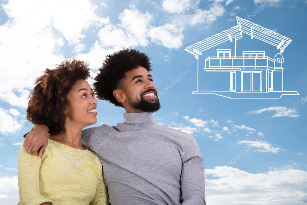 Smiling Portrait Of A Young Couple Dreaming Of The Drawn House Against Blue Sky