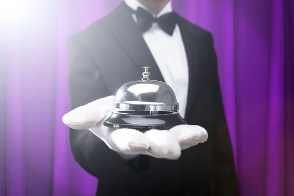 Midsection Male Waiter Holding Service Bell Hand Purple Curtain — Stock Photo, Image