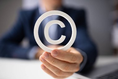 Person Holding White Copyright Sign In Hand clipart