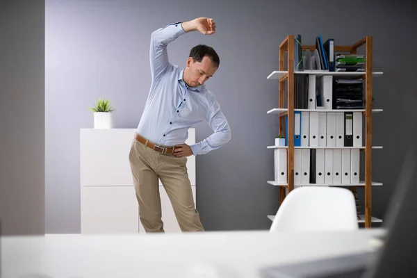 Portrait Of A Young Businessman Stretching In Office