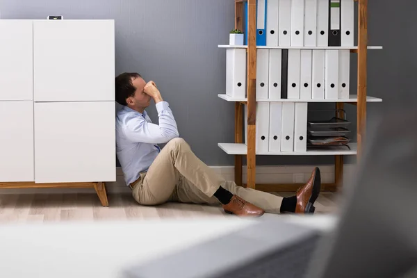 オフィスの部屋の床に座っている悲しい若い男 — ストック写真
