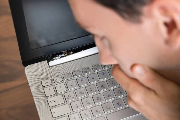 Man Looking At Damaged Laptop Computer With Broken Screen Attachment