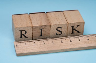 Close-up Of A Risk Word On Wooden Blocks Arranged Behind The Ruler On Blue Background clipart