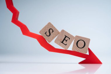 Tahta bloklardaki Seo Harfleri Gri Arkaplana Karşı Kırmızı Azalan Yön Oku Düzenlendi
