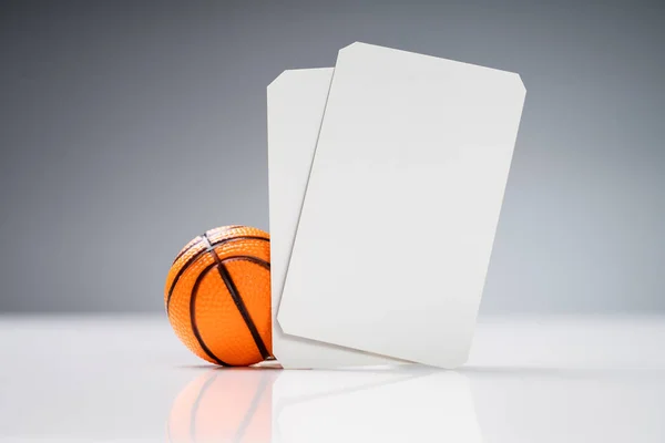 Miniatur Basketball Mit Weißen Blanko Tickets Auf Reflektierendem Schreibtisch Vor — Stockfoto