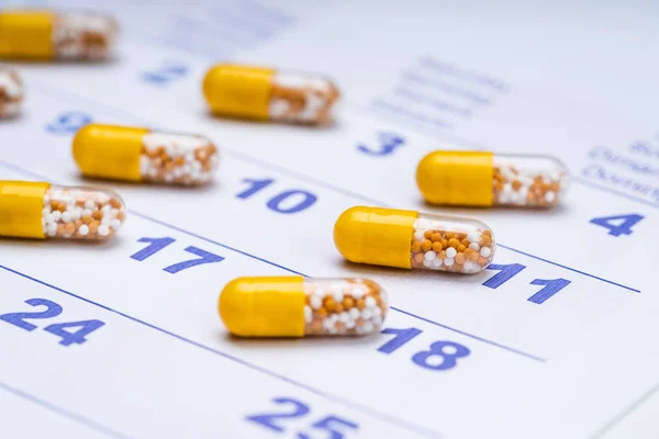 Primo Piano Delle Capsule Trasparenti Gialle Sulle Date Del Calendario — Foto Stock