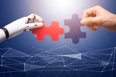 Robot ve İnsanın Eli Teknoloji Arkaplanındaki Kırmızı ve Mavi Yapboz Parçalarını Birleştiriyor