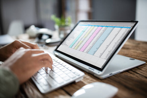 Close-up Of A Person's Hand Typing On Laptop Over Wooden Desk