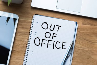 Not defterinde, dizüstü bilgisayar ve dijital tabletin yanında bulunan ofis dışı ileti.