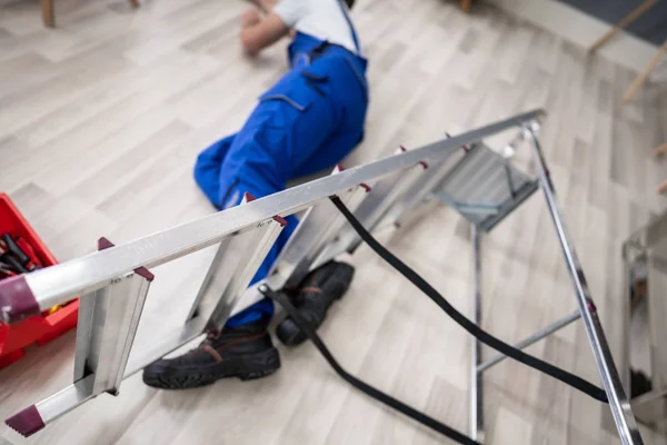Bewusteloze Klusjesman Viel Van Ladder Met Apparatuur Liggend Vloer — Stockfoto