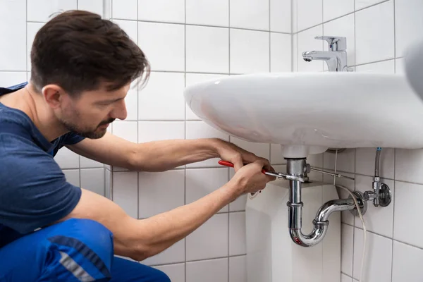 浴室の流しを固定する若い配管工 — ストック写真