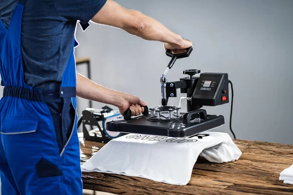 Man Printing On T Shirt In Workshop