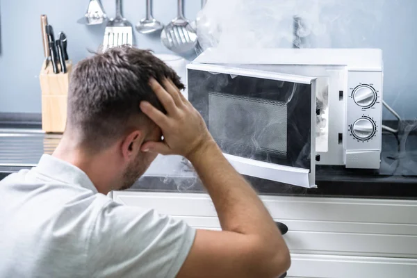 Young Man Spraying Fire Extinguisher Microwave Oven Kitchen — Stock Photo, Image