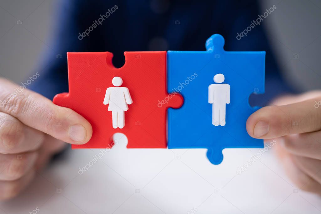 A Person's Hand Placing Blue Male Piece Beside Red Male Jigsaw Puzzle