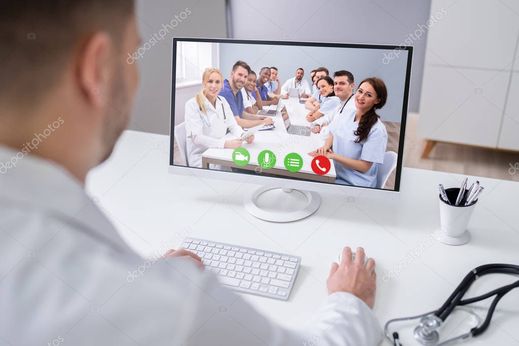 Young Male Doctor Video Chatting On Laptop In Clinic