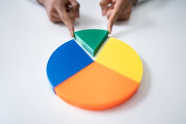 High Angle View Of Businessperson's Hand Placing A Last Piece Into Pie Chart clipart