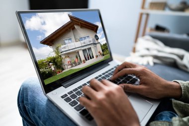 Bilgisayardaki bir evin fotoğrafına bakan bir iş adamının yakın plan fotoğrafı.