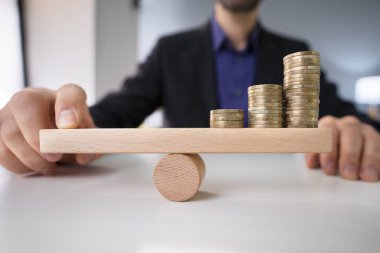 Yakın çekim Dengeleme bir işadamının'ın el parmak ile ahşap tahterevalli sikkelerinde Resepsiyon üzerinde yığılmış.
