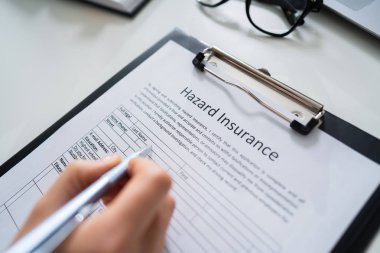Person Filling Hazard Insurance Form At Desk clipart