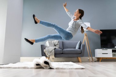 Photo Of Woman Stumbling With A Carpet In The Living Room At Home clipart