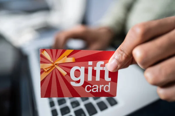 Mann Hält Rote Geschenkkarte Während Auf Laptop Tastatur Tippt — Stockfoto